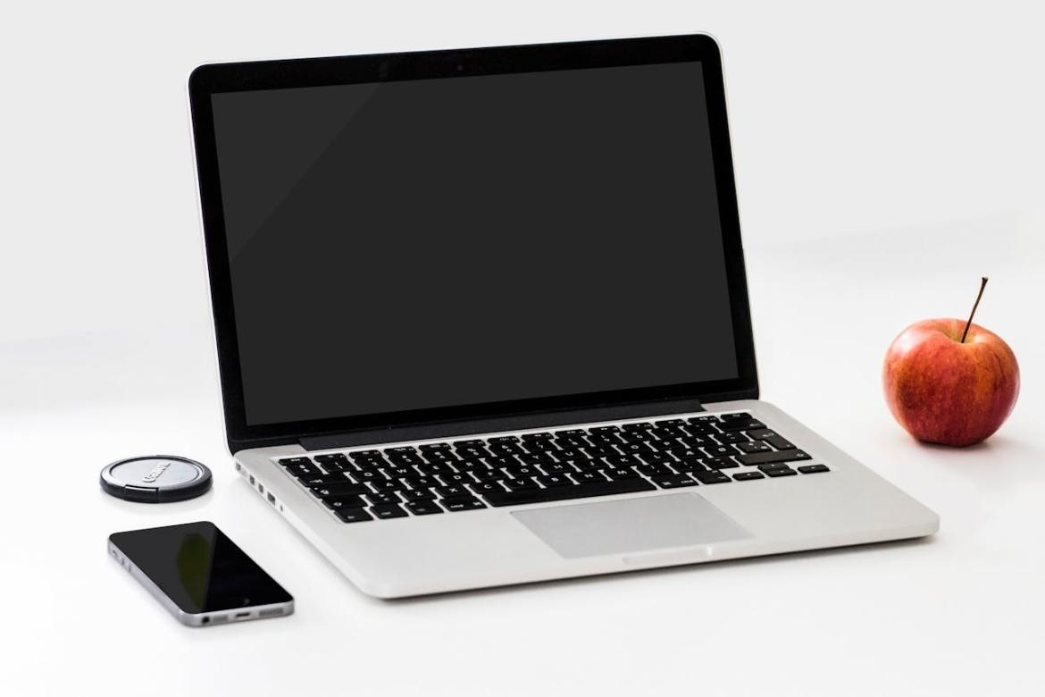 laptop next to a phone and an apple