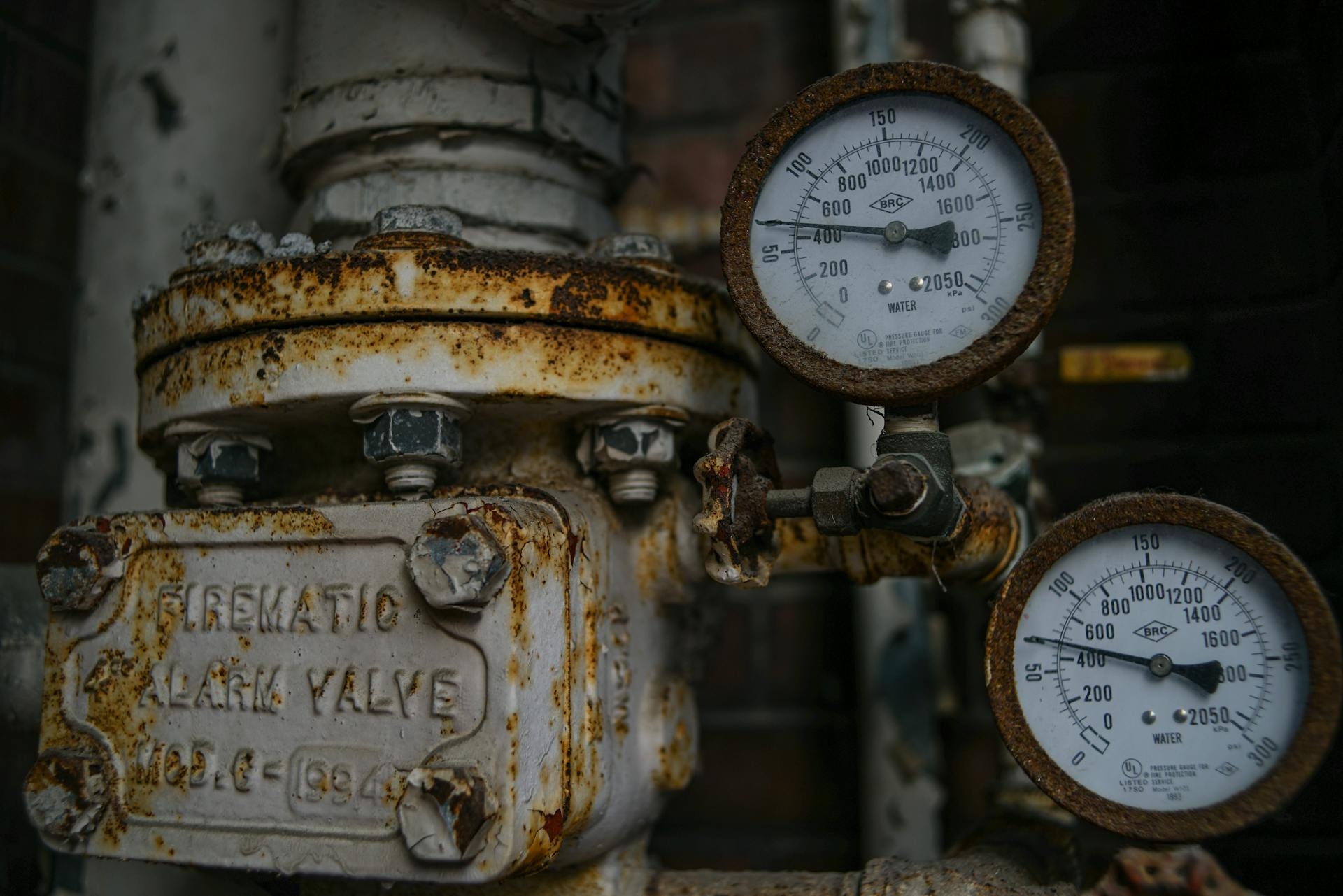 A rusty analog gauge with pipes