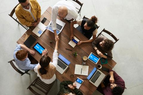 People sitting around a table with computers and tablets