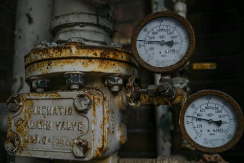 A rusty analog gauge with pipes